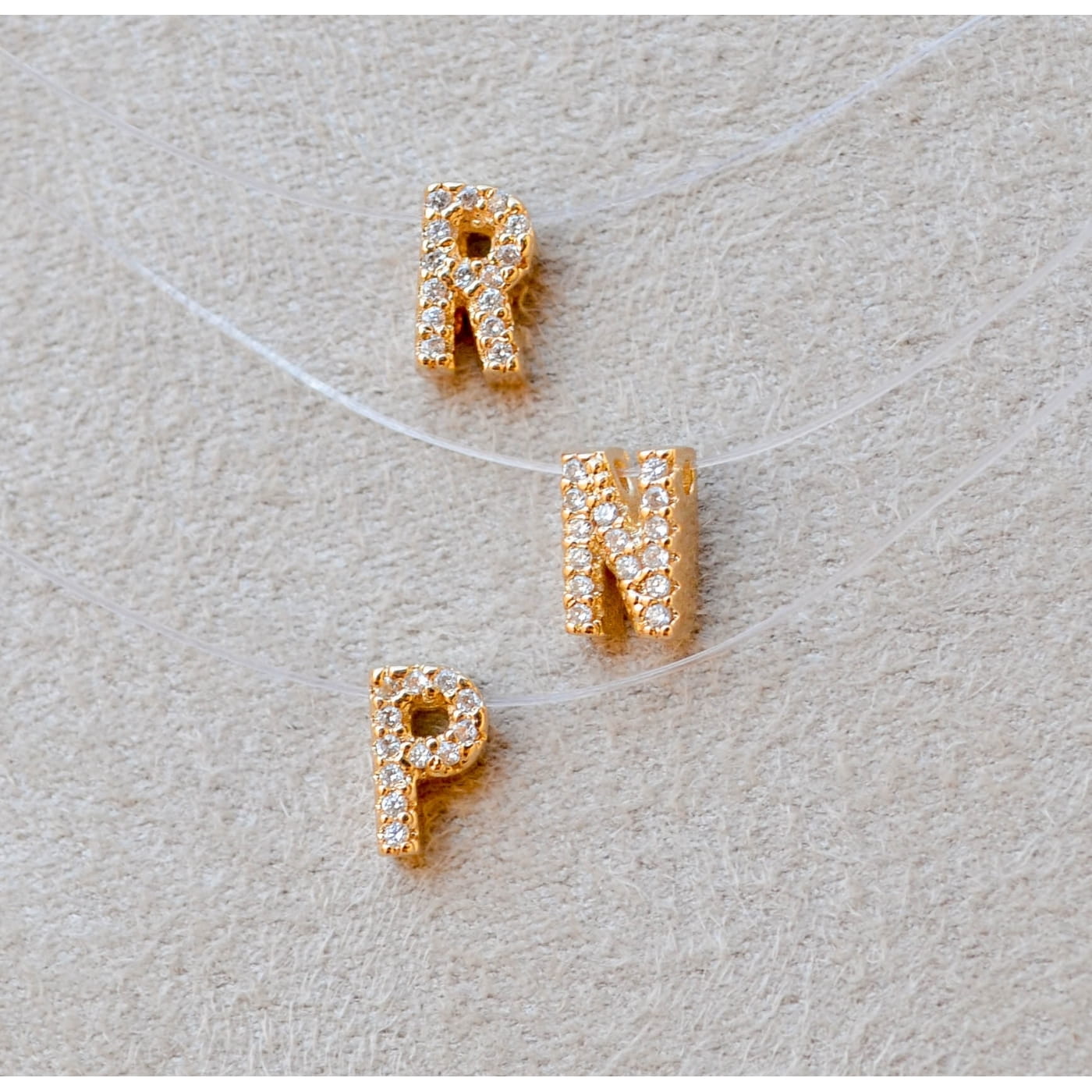 COLAR DE FIO DE NYLON COM PINGENTE DE LETRAS CRAVEJADAS 45CM